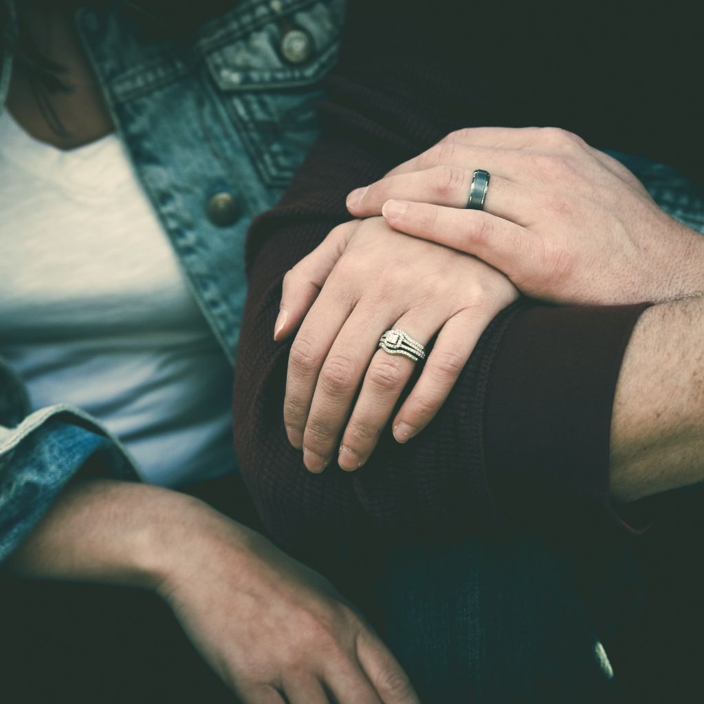 Close-up of a couple's hands together, showcasing their wedding rings, symbolizing unity and commitment.
