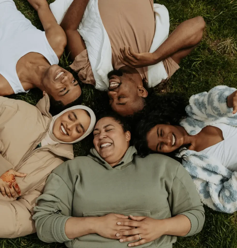 A group of diverse individuals lying on the ground, smiling and relaxed