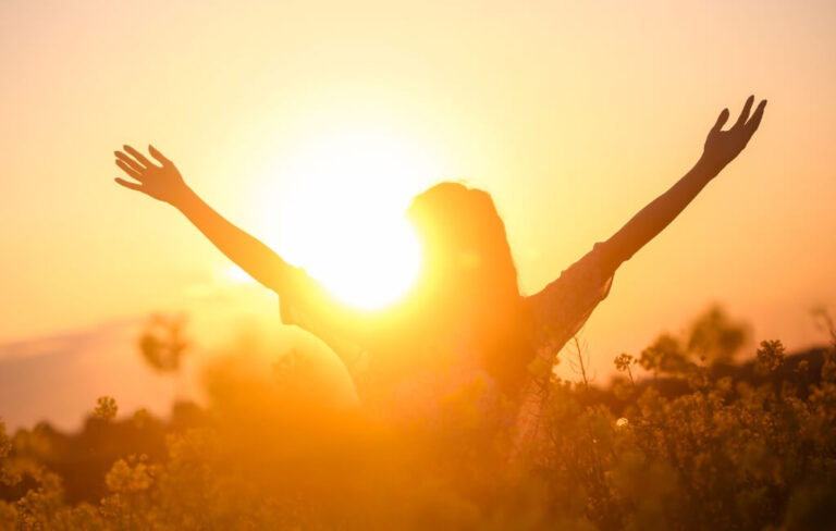 Woman with arms open towards the sun, symbolizing liberation from anxiety