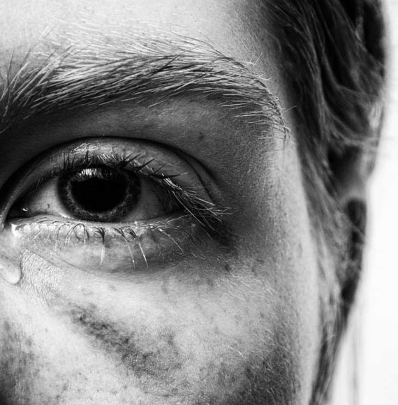 Close-up of a tearful eye, reflecting personal pain and trauma.