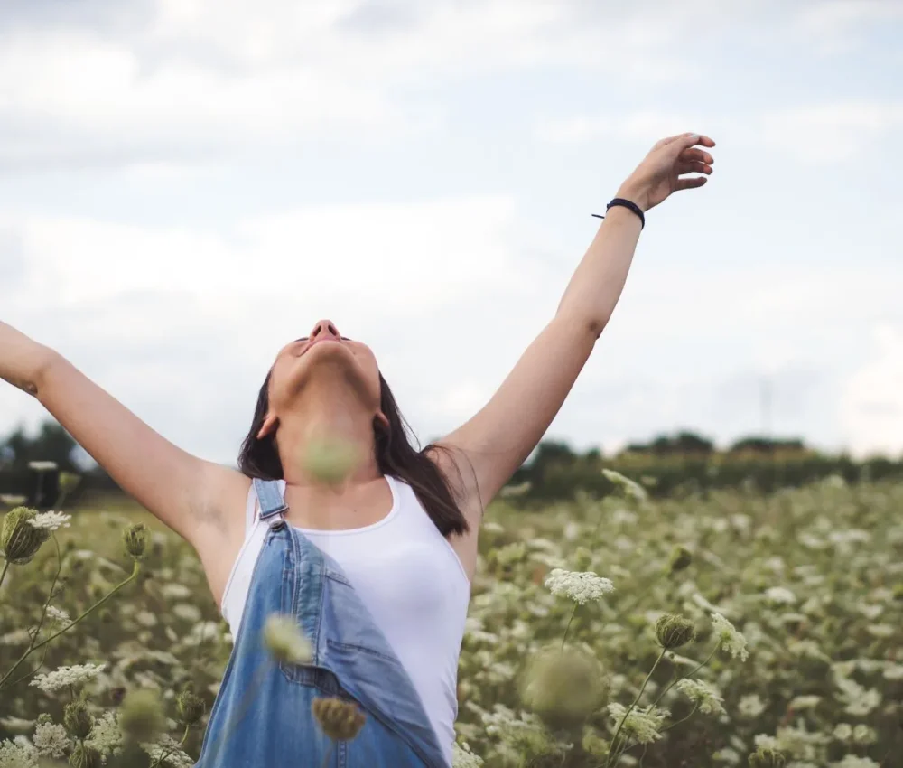 Woman with arms wide open in a field, symbolizing relief and joy after therapy.